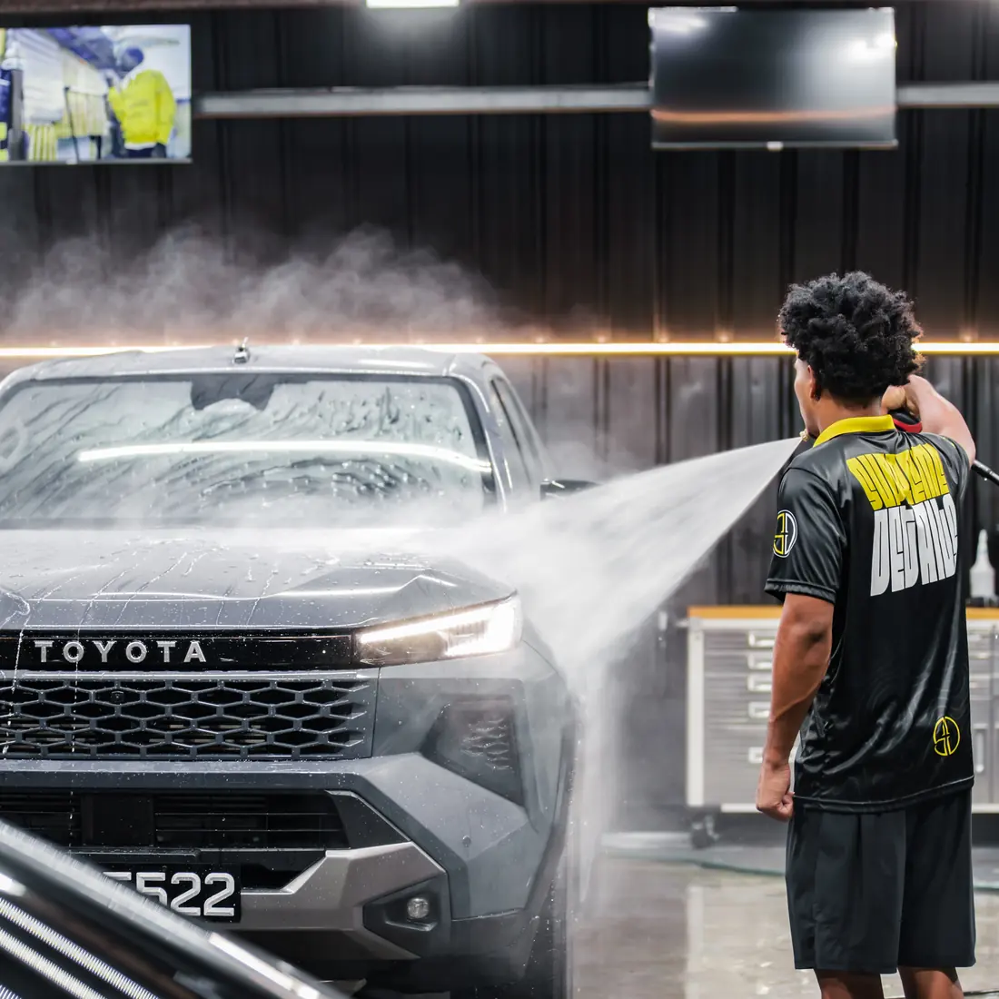 Supreme Details detailer pressure-rinsing a grey Toyota in the wash bay
