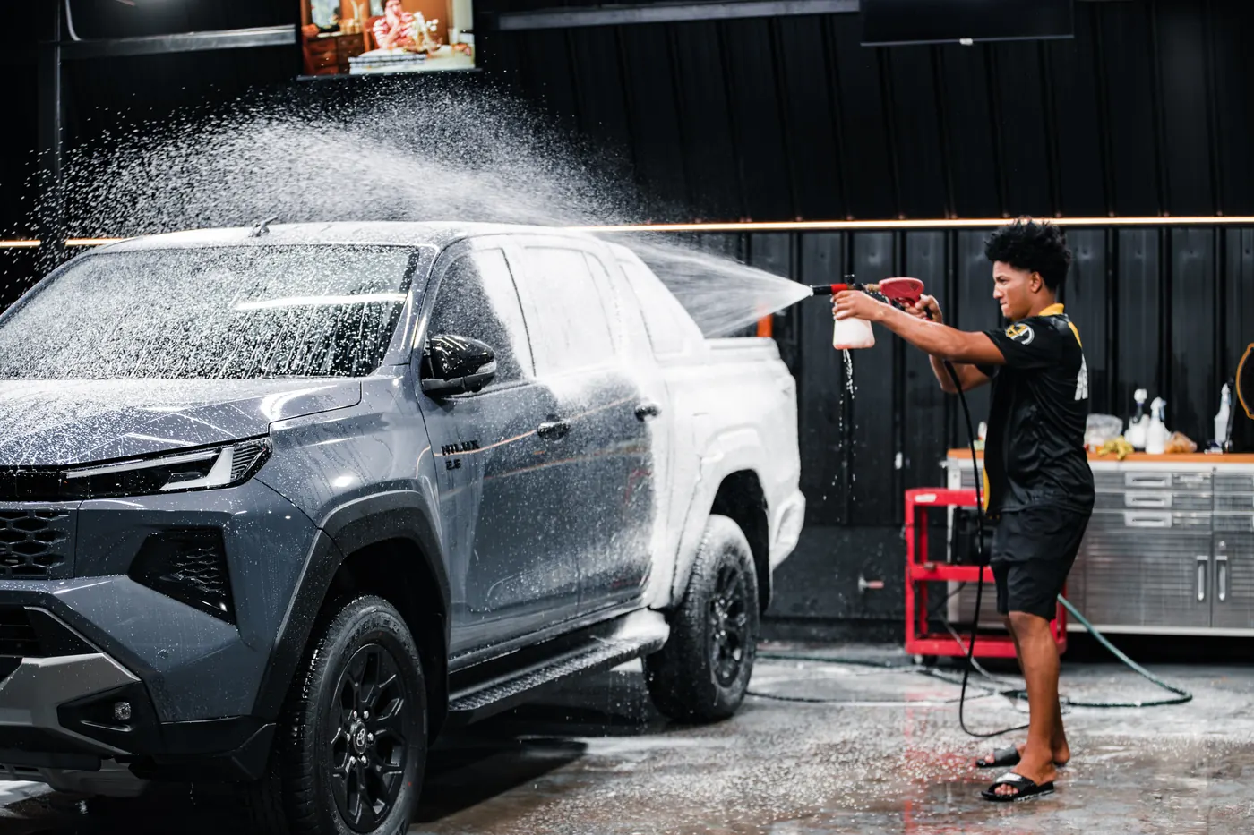 Detailer spraying a grey pickup with snow foam in the Supreme Details wash bay